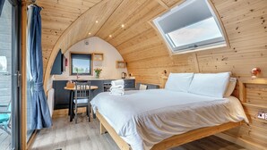A cozy, wooden cabin-style room with a bed, a desk, and a window.