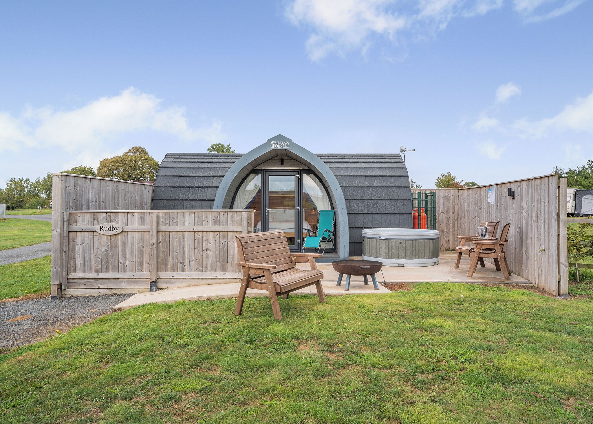Una estructura de madera con una placa, un jacuzzi y asientos al aire libre.