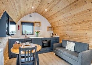 A cozy cabin interior with a dining area, kitchenette, and a sofa. - 0 bedroom accommodation in Great Busby (Great Busby)