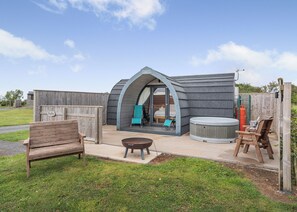 Un espace extérieur accueillant avec un banc en bois, un jacuzzi et un coin salon abrité.