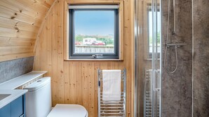 A wooden cabin bathroom with a window, a shower, and a toilet.