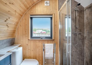 A wooden cabin bathroom with a window, a shower, and a toilet. - 0 bedroom accommodation in Great Busby (Great Busby)