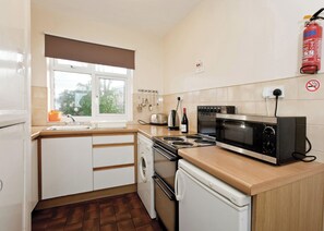 A compact kitchen with a washing machine, a microwave, a toaster, and a fire extinguisher.