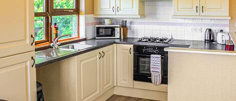 A compact kitchen with a sink, microwave, stove, and cabinets.