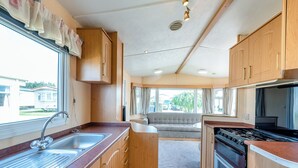 A compact kitchen with a sink, stove, and wooden cabinets.