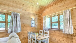 L’intérieur d’un chalet en bois, avec une table à manger, des chaises et un tableau encadré accroché au mur.