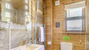 Une salle de bain avec un lavabo en marbre, une cabine de douche en verre, des murs en bois et des toilettes.