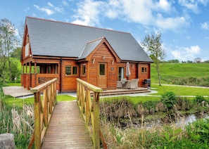 Une cabane en bois dotée d’une terrasse, d’un espace salon extérieur abrité et offrant une vue sur un paysage verdoyant.