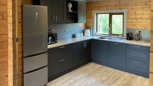 Una cocina moderna con armarios oscuros, electrodomésticos de acero inoxidable y un ventanal con vistas al verdor.