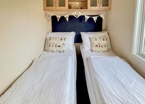 A room with two single beds, a dark headboard, and a small cabinet above.