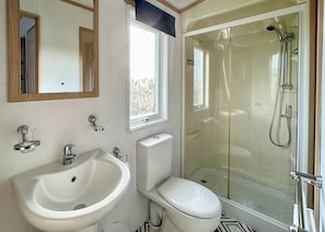 Un baño con lavamanos, inodoro y ducha con mampara de vidrio.