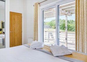 A bedroom with a bed, a wooden door, and a large window with curtains.