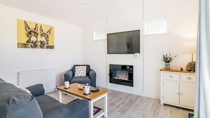 A modern living room with a sofa, a coffee table, a fireplace, a TV, and a cabinet. - 1 bedroom accommodation in Cannington (Cannington)