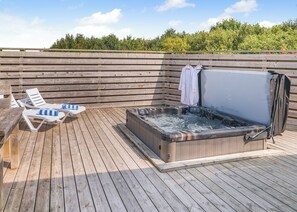 Eine Holzterrasse mit Liegestühlen und einem Whirlpool.