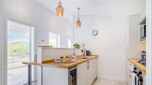 A modern kitchen with a wooden countertop, stainless steel appliances, and pendant lighting. - 1 bedroom accommodation in Cannington (Cannington)