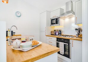 A modern kitchen with white cabinetry, a microwave, a kettle, and a toaster.