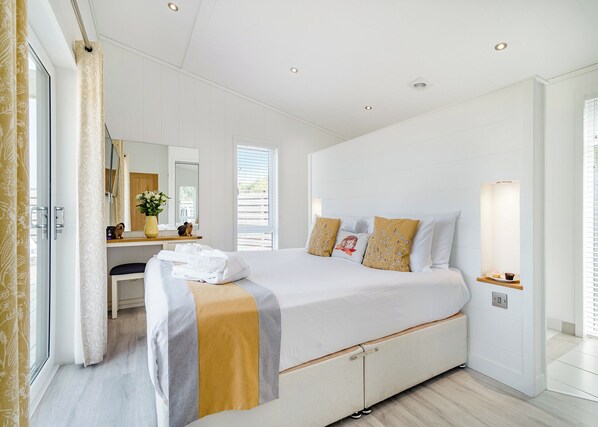 Una habitación de hotel moderna con una cama grande, un escritorio con espejo y una ventana con persianas.