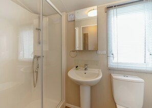 Une salle de bain avec une douche à parois de verre, un lavabo, des toilettes et un miroir.