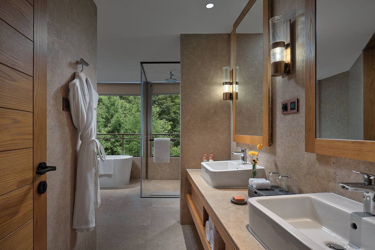 Un baño moderno con dos lavamanos, un espejo grande y una bañera.
