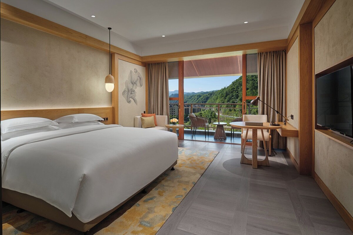 Une chambre d’hôtel moderne dotée d’un grand lit, d’un coin repas et d’une télévision.