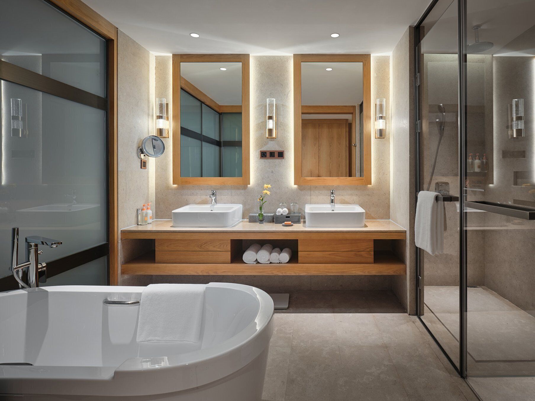 A modern bathroom with two sinks, a large bathtub, and a glass shower enclosure.