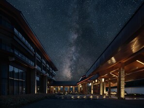 Ein Hotel mit überdachtem Außenbereich, großen Fenstern und Blick auf den Nachthimmel.