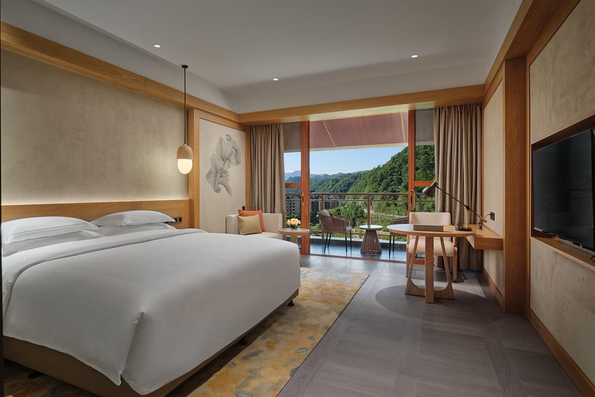 Una habitación de hotel moderna con una cama grande, un área de comedor y un televisor.