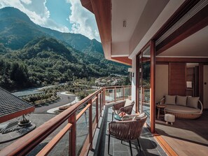Un balcón con vistas a un paisaje montañoso, mobiliario de mimbre y un diseño de interiores moderno.