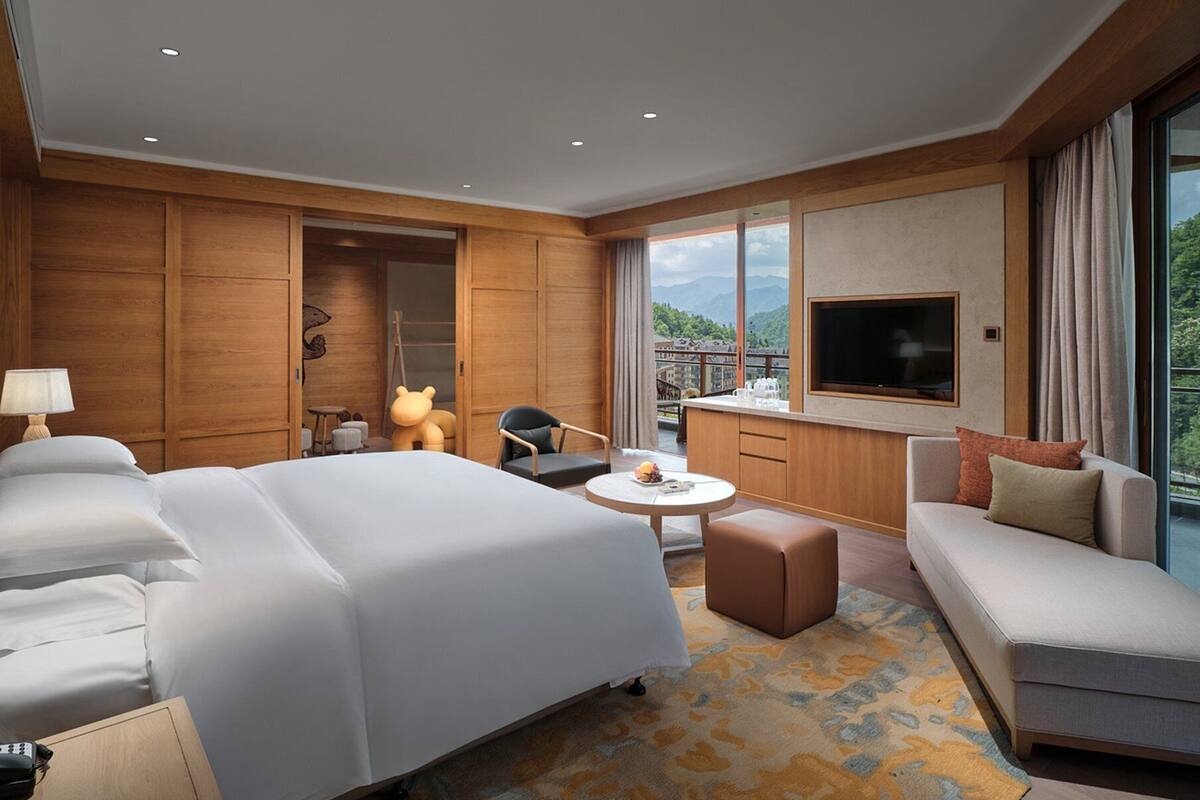 Una habitación de hotel moderna con una cama grande, un sofá, una mesa de comedor y un televisor.