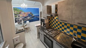 Cocina compacta con vistas a un pueblo costero, un candelabro y un salpicadero con estampado de cuadros.