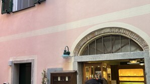 Un edificio de fachada rosa, contraventanas verdes y puerta de madera.