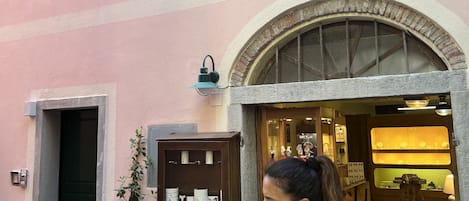 Un edificio de fachada rosa, contraventanas verdes y puerta de madera.