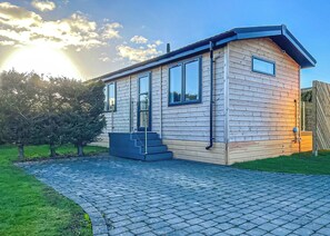 Une maison moderne de plain-pied, dotée d’une allée pavée, de grandes fenêtres et d’une façade en bois.