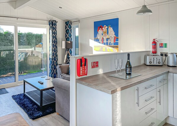 A modern kitchen with a large island, a dining area with a table and chairs, and a view of the outdoors.