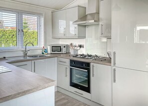 Una cocina moderna con armarios blancos, microondas integrado, estufa y horno.