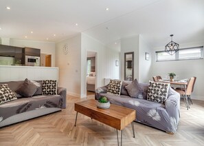 A modern living room with a sofa set, a wooden coffee table, and a dining area with chairs and a table.