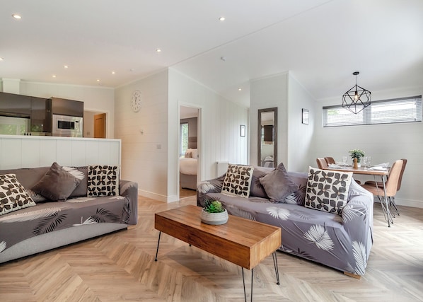 Een moderne woonkamer met een zithoek, een houten salontafel en een eethoek met stoelen en een tafel.