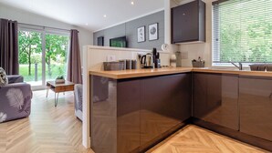 Una cocina moderna con encimera de madera, armarios oscuros y un amplio ventanal con persianas.