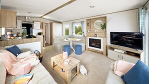 A modern RV interior with a kitchen, dining area, living room, and a TV. - Stylish and modern caravan with one double and one twin. (Clarach Bay, Nr Aberystwyth)