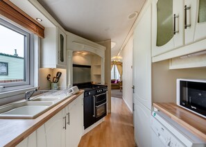 Una cocina estrecha con estufa, horno y fregadero.