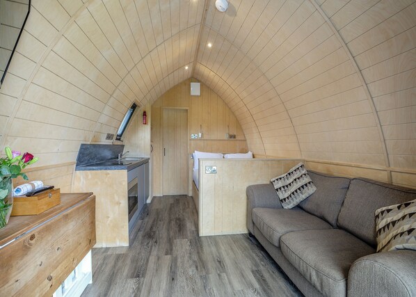 Un interior compacto de madera con kitchenette, un sofá y un pequeño comedor.