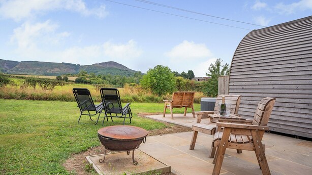 An outdoor patio with a fire pit, wooden chairs, and a table. - 1 bedroom accommodation in Great Busby (Great Busby)