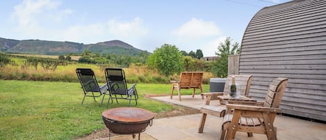 Eine Terrasse im Freien mit einem Feuerkorb, Holzstühlen und einem Tisch.