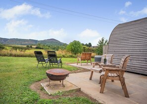 An outdoor patio with a fire pit, wooden chairs, and a table. - 1 bedroom accommodation in Great Busby (Great Busby)