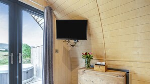 A wooden interior with a sliding glass door, a mounted TV, a wooden dresser, and a vase with flowers. - 1 bedroom accommodation in Great Busby (Great Busby)
