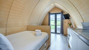 A cozy room with a bed, a small kitchenette, a TV, and a sliding door leading to an outdoor area. - 1 bedroom accommodation in Great Busby (Great Busby)