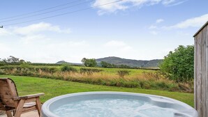 A hot tub with a wooden chair, a wooden deck, and a view of a grassy field with hills in the background. - 1 bedroom accommodation in Great Busby (Great Busby)