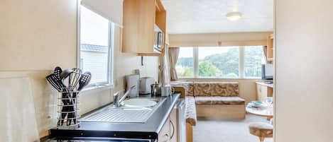 Una cocina compacta con estufa, lavamanos y ventana.