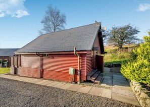 A red metal shed with a sloped roof, a satellite dish, and a small window.