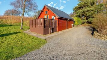 A red wooden building with a gravel driveway and a fenced area.